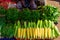 Ripe corn in drops of water and a variety of greens close-up. Local farmer vegetable market in Asia. Counter with corncobs