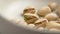 Ripe cracked pistachio nuts with green kernels in a kitchen bowl