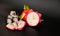 Ripe cut fruit of exotic fruit Pitaya or Dragon Heart with ice cubes on a black background