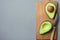 Ripe Evenly Halved Organic Australian Avocado with Pit on Wooden Cutting Board with Knife Grey Background. Healthy Lifestyle Vegan