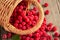 Ripe forest raspberries scattered from a small basket on a wooden table, top view