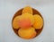 Ripe fragrant apricots on a small brown ceramic plate on a white background.