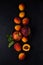 Ripe fresh bright apricots and peaches lie in scattering on a clay plate and on a dark surface. view from above. artistic moody