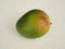 A ripe fresh mango fruit covered with water droplets lies on the table