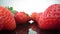 Ripe, fresh, natural strawberries in reflection, in extreme macro, close up. Movement forward, backward.