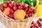Ripe fresh organic peaches, sweet cherries in a fruit wicker basket on wood garden table, herbs, melon, summer, outdoors, harvest,