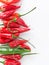 Ripe fresh organic red and green hot peppers arranged in border on white stone marble background. Healthy spices digestion
