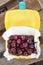 Ripe fresh tasty bio cherries in plastic lunchbox oudoors. Organic sweet berries takeaway quick food for picnic. Wooden table on b