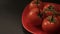 Ripe fresh tomatoes branch lies on red plate on the table