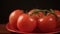 Ripe fresh tomatoes branch lies on red plate on the table