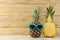 Ripe fruit pineapple in sunglasses on a natural wooden background. summer. space for text