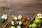 Ripe green apples in wooden box with branch of white flowers, glass and bottle of cider on a wooden table