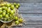 Ripe green gooseberries in a glass transparent bowl on a wooden background. Harvest concept. Vegetarian food.Top view, copy space.