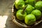 Ripe green organic pears in vintage wicker basket on aged wood kitchen table, sunlight flecks, rustic style