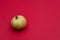 Ripe green pomegranate lies on a red background.