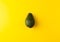 Ripe juicy avocado isolated on a yellow solid background. Vegan, vegetarian, raw food theme.