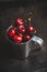 Ripe and juicy cherries in old metal cup on the dark rustic background