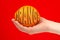 Ripe juicy delicious orange in hand isolated on red background. Healthy eating and dieting concept. Word ORANGE