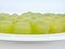 Ripe juicy green grapes lying flattened on a white plate