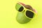 Ripe juicy green and red mango in sunglasses on pastel yellow background.Copy space. minimalistic style