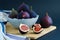 Ripe juicy purple figs whole and in pieces, in bowl on wooden board