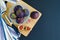 Ripe juicy purple figs whole and in pieces, in bowl on wooden board, on black dark background