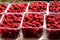 Ripe juicy raspberries in plastic containers on market stall. Fresh organic berries from ecofarm