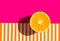 Ripe juicy raw orange cut in half on duotone pink striped background. Citrus fruits healthy diet vitamins concept. Trendy poster