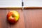 Ripe juicy red apple near the book and pen. Useful food during a