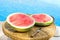 Ripe Juicy Seedless Watermelon Cut in Half Slices on Plate on Rattan Table by Swimming Pool. Sunlight. Seaside Vacation Relaxation