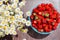 Ripe juicy strawberries in a bowl on the table, next to a bouquet of daisies in a vase