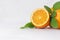 Ripe juicy yellow half oranges with fresh green leaves on white wood board, closeup, copy space.