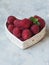 Ripe large raspberry and a sprig of mint in a bowl in the shape of a heart