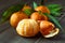Ripe Mandarin fruit peeled open and place on old rustic look timber with group of mandarin fruits and leaves out of focus on the