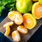 Ripe Mandarin fruit peeled open and place on old rustic look timber with group of mandarin fruits and leaves. Winter fruits