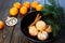 Ripe mandarine with leaves, tangerine mandarine orange in black bowl on wooden table background. Citrus fruits Mandarins in plate.