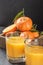 Ripe mandarins with leaves and juice glass on stone background