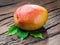 Ripe mango fruit with mango leaves on wooden background.