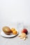 Ripe mango on a plate, tangerines, peach fruit and a glass of water on a table against white wall. Still life