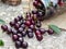 Ripe maroon cherry spills from a glass jar on the burlap