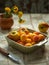 Ripe nectarines and apricots in a ceramic square plate of olive color and a small bouquet of mother-and-stepmother on a