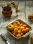 Ripe nectarines and apricots in a ceramic square plate and a small bouquet of mother-and-stepmother on a light table
