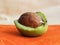 Ripe nut with an open green shell on the orange table. A clear walnut from a walnut tree