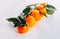 Ripe orange fresh mandarin on a white background. Five tangerines with green on a white background