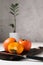 Ripe orange persimmons on the dark wood cutten board. Rustic background with green zamioculcas. Front view