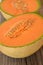 Ripe organic cantaloupe melon muskmelon, mushmelon, rockmelon cut in half on old wooden table.