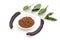 Ripe organic carob fruit pods, green leaves from locust tree and carob powder in plate on white background. Healthy alternative to