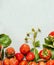 Ripe organic garden strawberries with green leaves and flowers on wooden background, top view