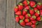 Ripe organic strawberries on dark plate on plank wood background, close up, healthy food, detox