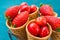 Ripe organic strawberries, glossy sweet cherries in waffle ice cream cones in wire basket, blue background, styled image